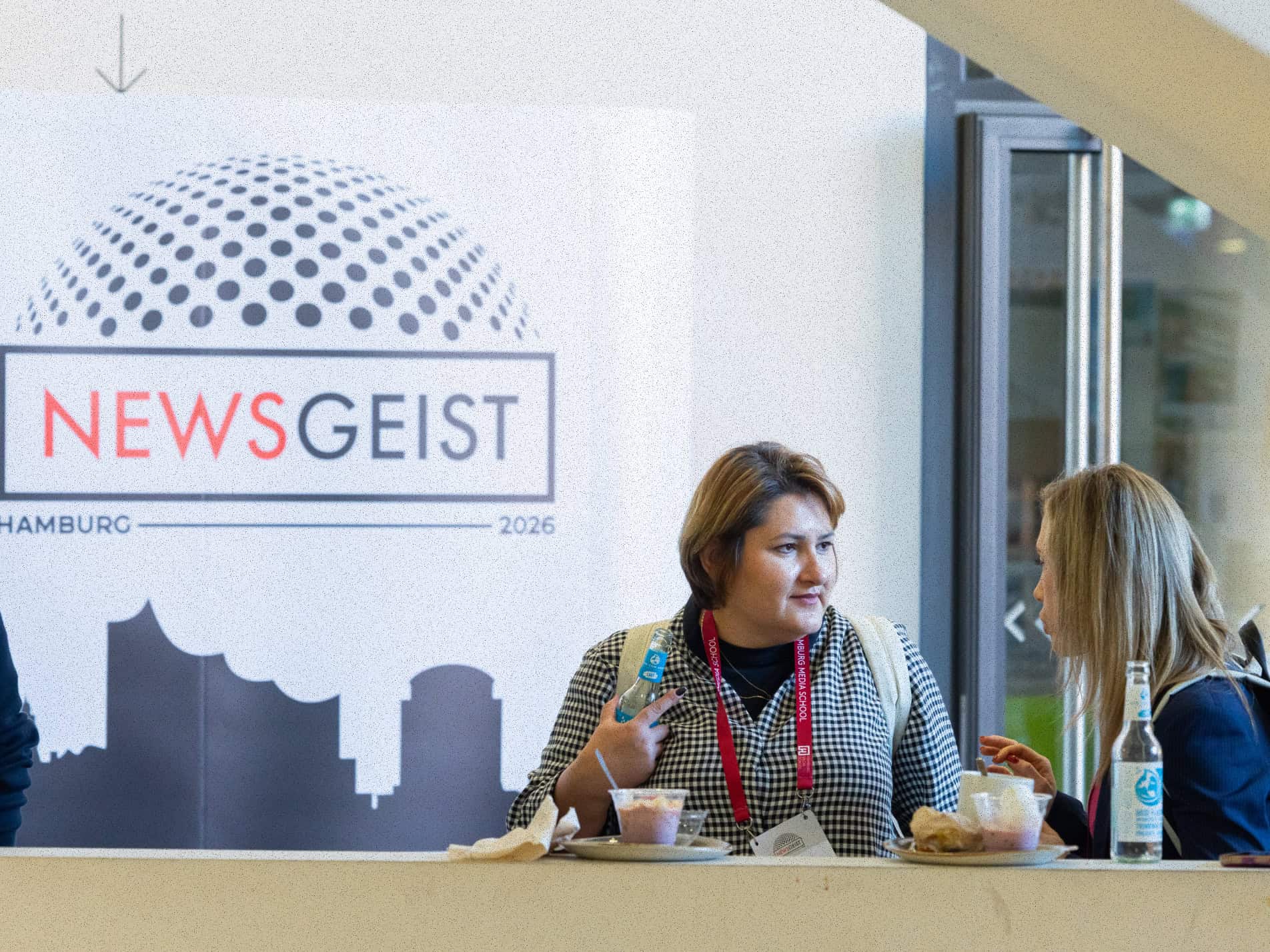 Two woman talking with a banner reading "newsgeist" in the background.