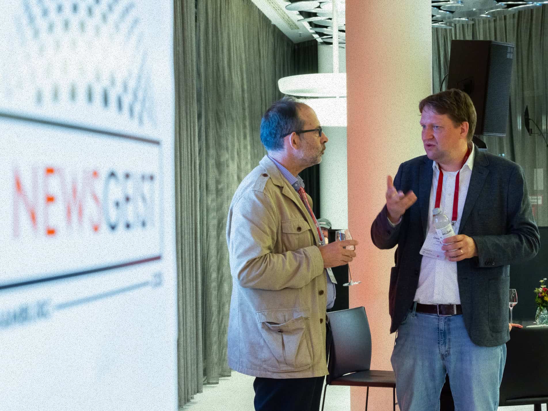 Two men talking with a banner in the background that reads "newsgeist."
