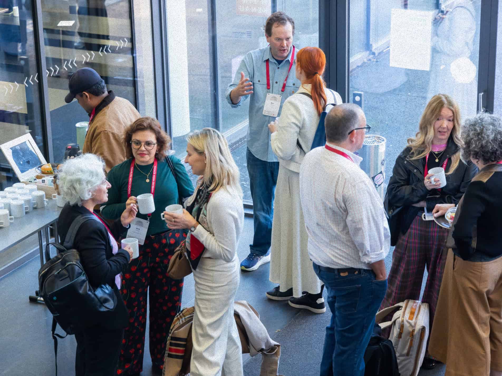 Groups of people standing in a front corridor and talking.