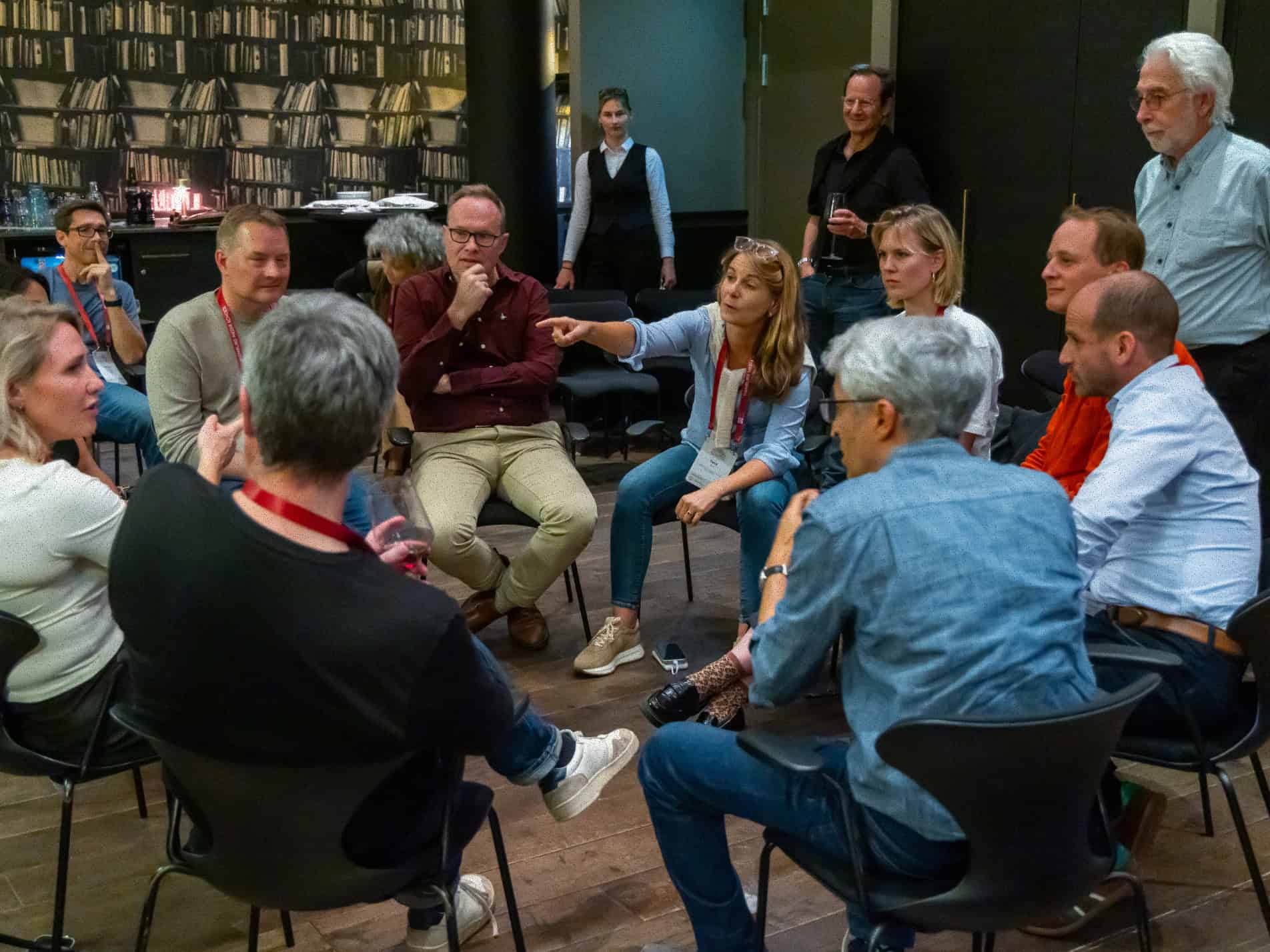 Group of individuals sitting in chairs in a circle while one individual is talking